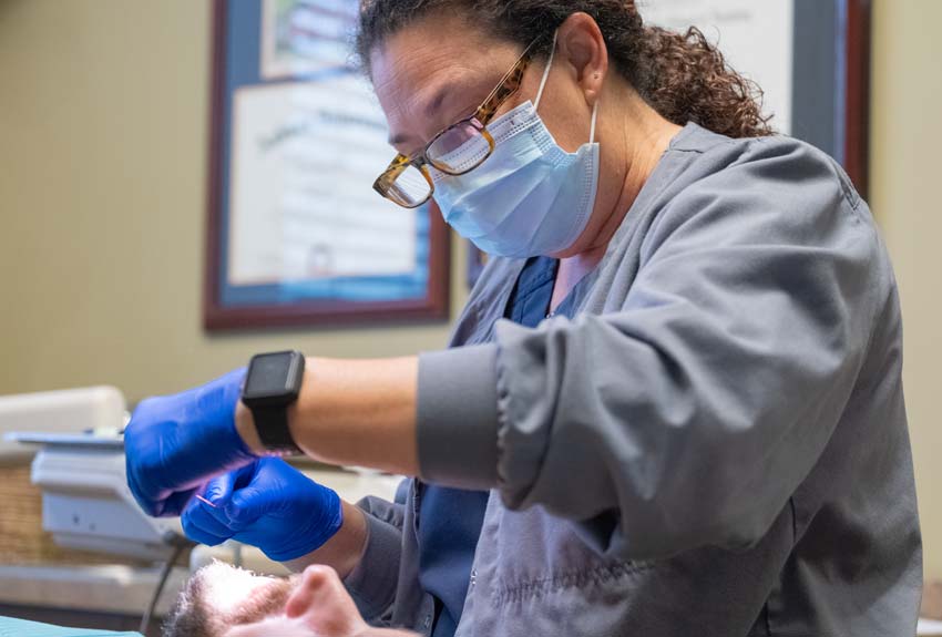 Dental hygenist flossing a middle aged man in a dental chair