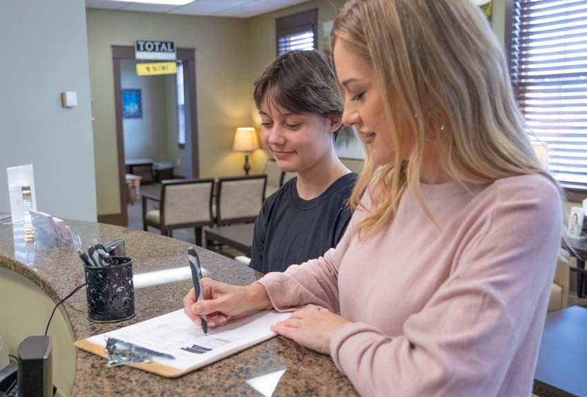 Happy mom and daughter signing paperwork at the front desk