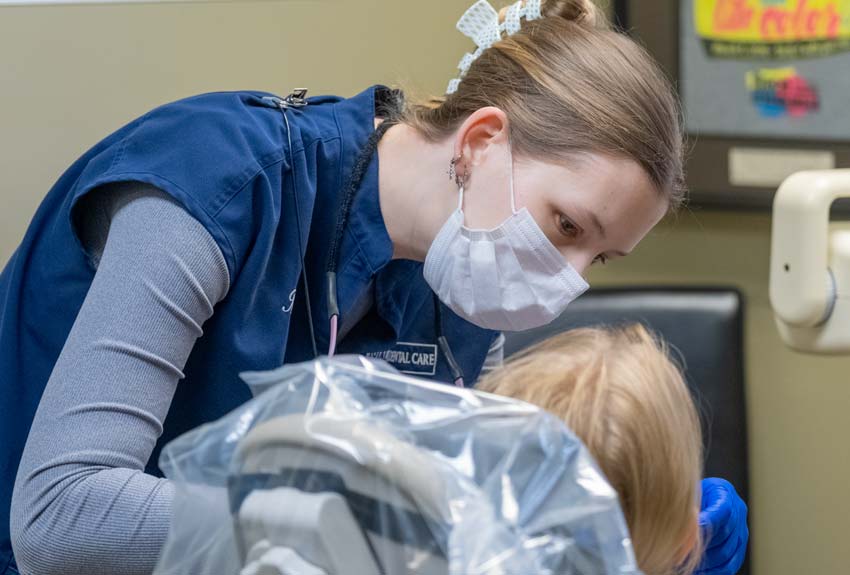 Dental hygenist examining a pediatric girl in a dental chair