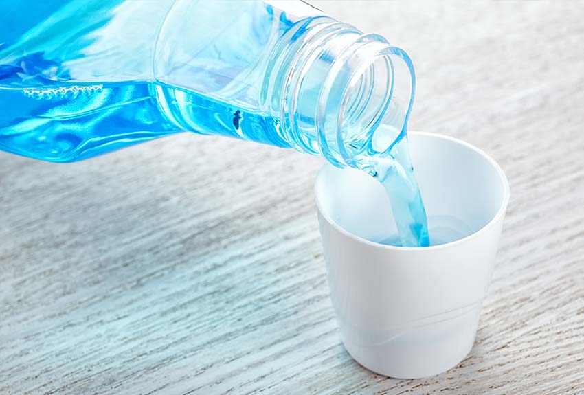 close-up of a bottle of mouthwash being poured into the container's cap
