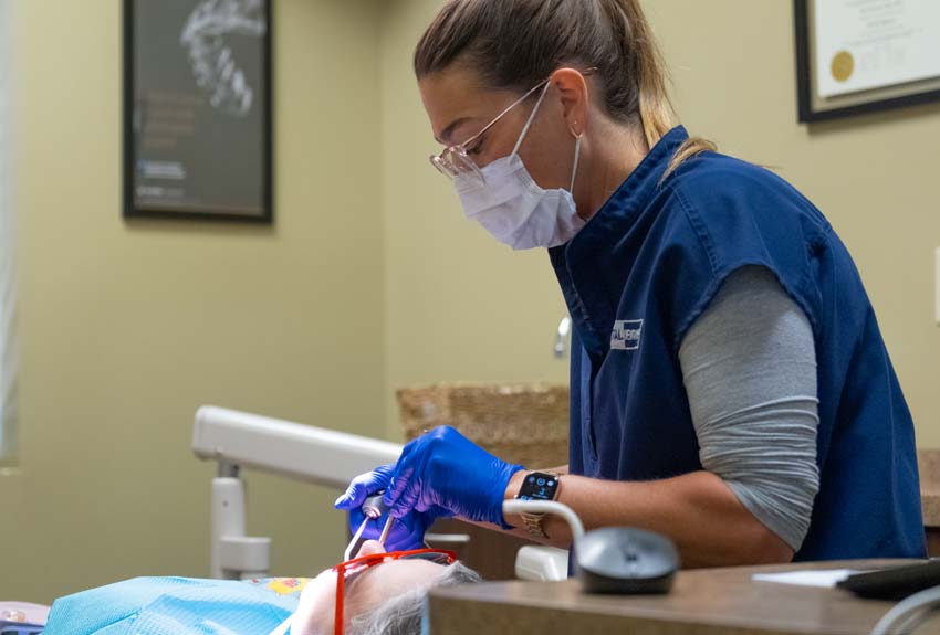 Dental hygenist performing a dental procedure on a middle aged woman
